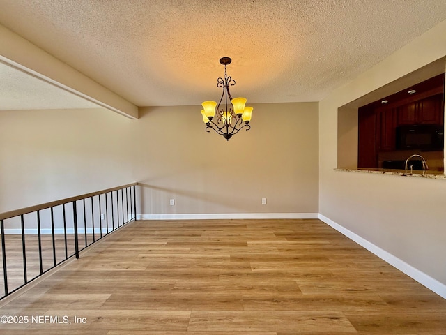 7779 Las Palmas Way Unit 114, Jacksonville, FL 32256 - unfurnished dining area featuring light wood-style floors, a textured ceiling, a chandelier, a sink, and baseboards