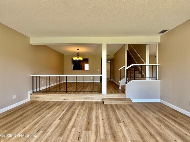 7779 Las Palmas Way Unit 114, Jacksonville, FL 32256 - empty room featuring a chandelier, wood finished floors, baseboards, stairs, and a textured ceiling