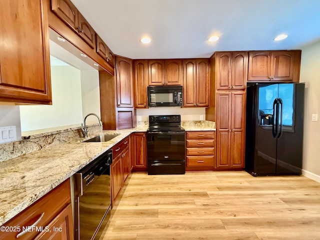 7779 Las Palmas Way Unit 114, Jacksonville, FL 32256 - kitchen with black appliances, a sink, light stone counters, recessed lighting, and light wood-type flooring