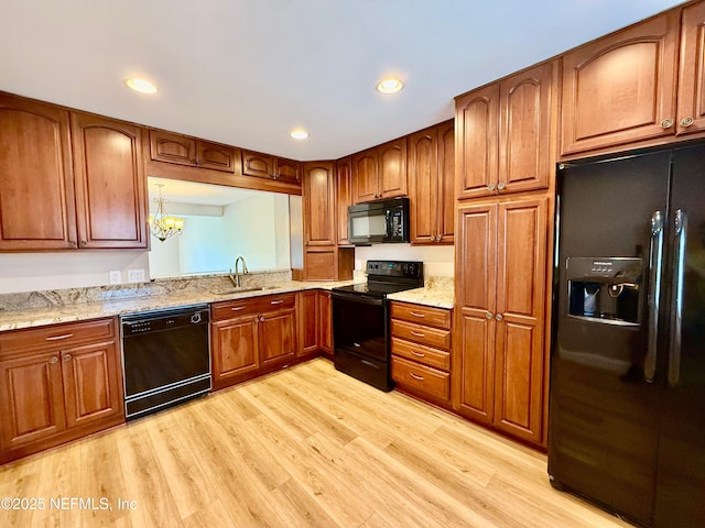 7779 Las Palmas Way Unit 114, Jacksonville, FL 32256 - kitchen with black appliances, a sink, light wood-type flooring, brown cabinetry, and light stone counters