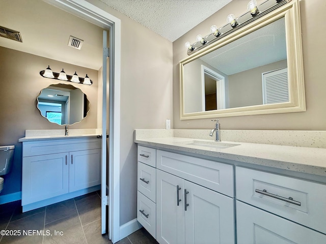 7779 Las Palmas Way Unit 114, Jacksonville, FL 32256 - bathroom featuring toilet, two vanities, baseboards, tile patterned flooring, and a textured ceiling
