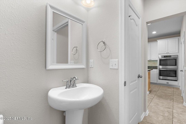 1011 Wetland Ridge Cir, Middleburg, FL 32068 - bathroom with a textured wall, tile patterned flooring, and a sink