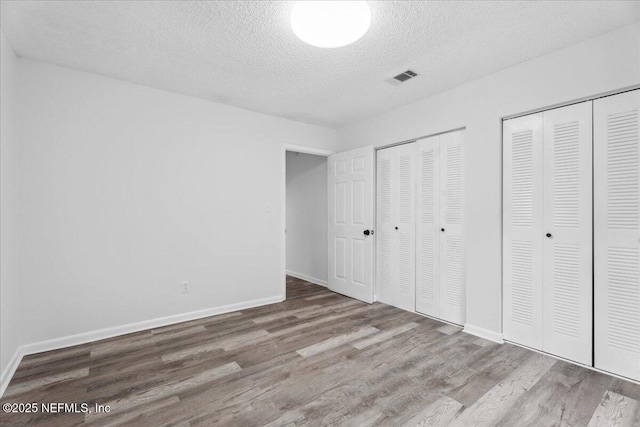 318 W Lafayette St, Starke, FL 32091 - unfurnished bedroom featuring multiple closets, wood finished floors, a textured ceiling, and baseboards