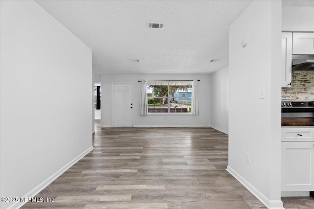 318 W Lafayette St, Starke, FL 32091 - unfurnished living room with light wood finished floors, a textured ceiling, and baseboards