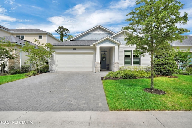 9813 Filament Blvd, Jacksonville, FL 32256 - view of front of home with an attached garage, decorative driveway, a front lawn, and stone siding