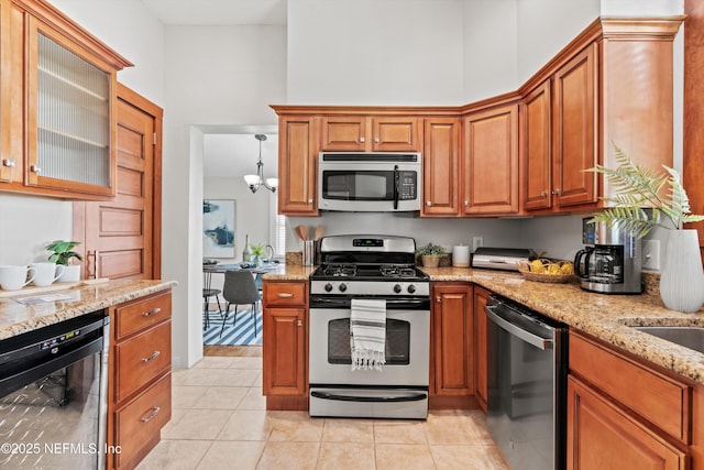 1819 Landon Ave, Jacksonville, FL 32207 - kitchen featuring appliances with stainless steel finishes, wine cooler, light stone counters, light tile patterned floors, and brown cabinetry