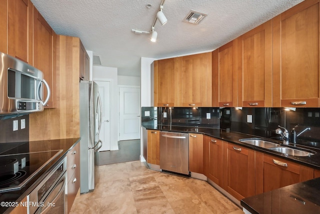 1431 Riverplace Blvd Unit 1707, Jacksonville, FL 32207 - kitchen featuring appliances with stainless steel finishes, a sink, brown cabinetry, and a textured ceiling