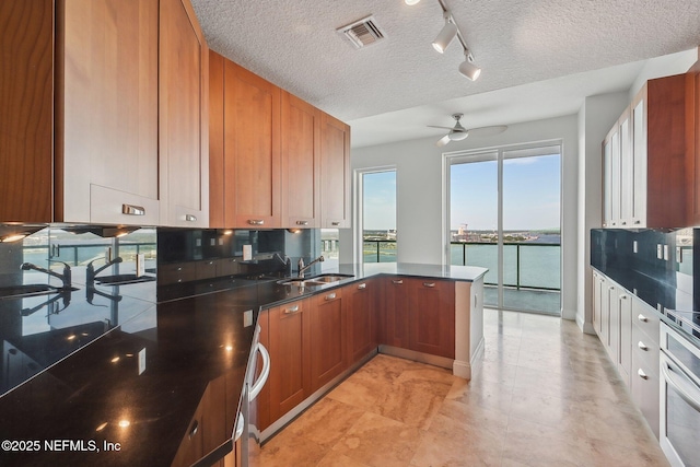 1431 Riverplace Blvd Unit 1707, Jacksonville, FL 32207 - kitchen with track lighting, a peninsula, a ceiling fan, wall oven, and brown cabinets