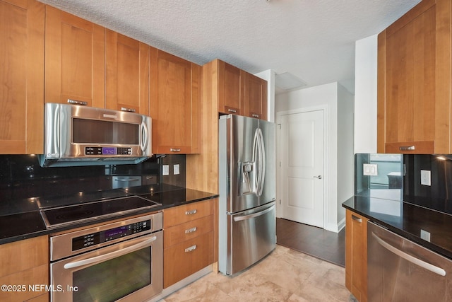 1431 Riverplace Blvd Unit 1707, Jacksonville, FL 32207 - kitchen featuring appliances with stainless steel finishes, brown cabinets, and a textured ceiling