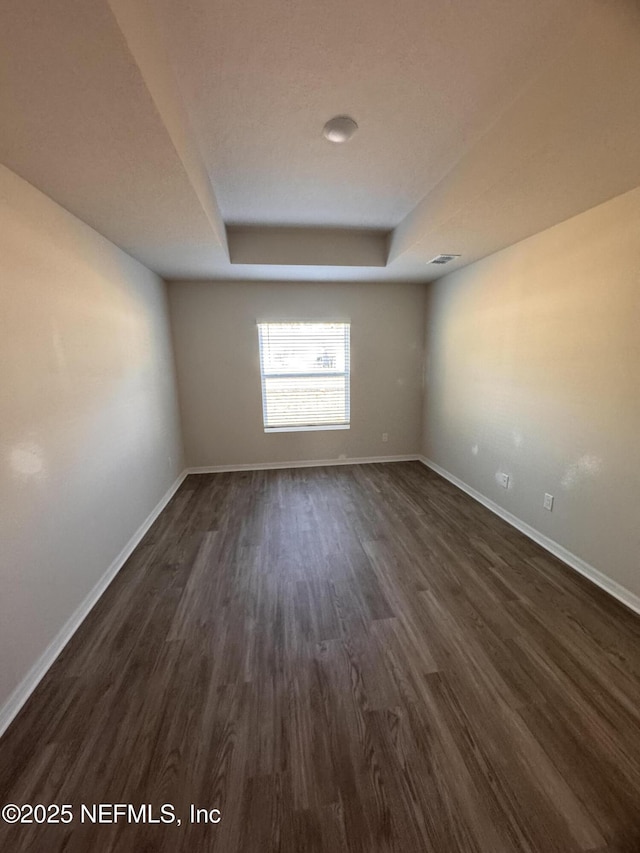 47 Laguna Forest Trl, Palm Coast, FL 32164 - empty room with a tray ceiling and dark wood-style flooring