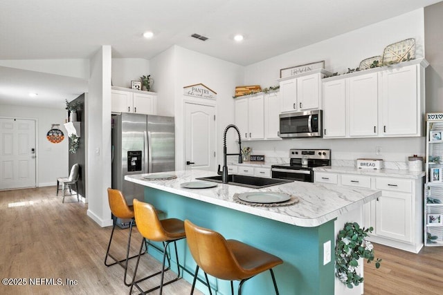 12097 Grand Herring Way, Jacksonville, FL 32219 - kitchen with stainless steel appliances, a sink, white cabinets, a kitchen breakfast bar, and a kitchen island with sink