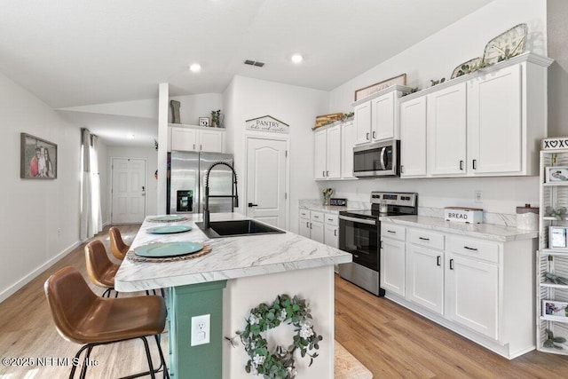 12097 Grand Herring Way, Jacksonville, FL 32219 - kitchen featuring appliances with stainless steel finishes, a sink, white cabinetry, a kitchen bar, and lofted ceiling