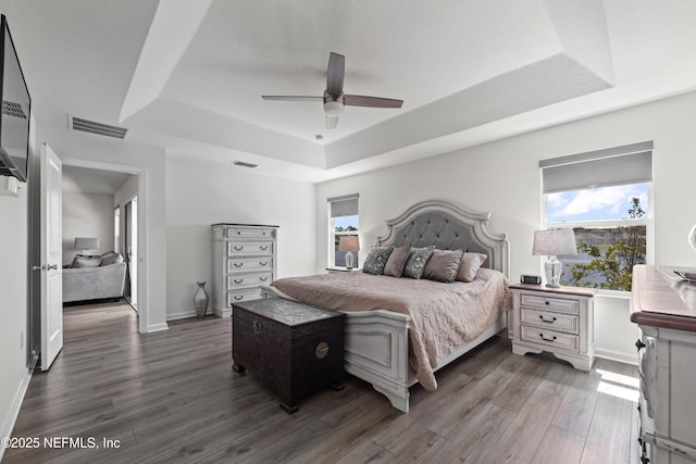 25 Windsor Ter, Palm Coast, FL 32164 - bedroom with a tray ceiling, multiple windows, wood finished floors, and a ceiling fan