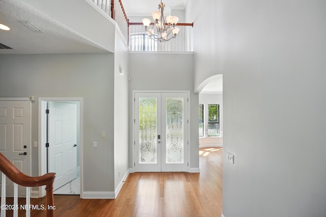 10065 Ecton Ln, Jacksonville, FL 32246 - foyer entrance featuring a high ceiling, arched walkways, wood finished floors, a chandelier, and french doors