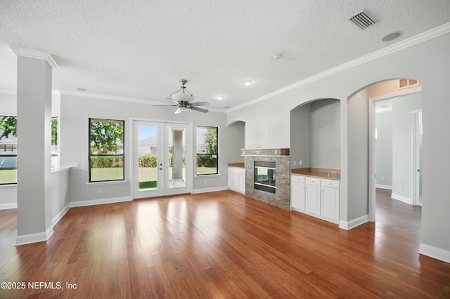 10065 Ecton Ln, Jacksonville, FL 32246 - unfurnished living room featuring wood finished floors, ceiling fan, a textured ceiling, a glass covered fireplace, and baseboards