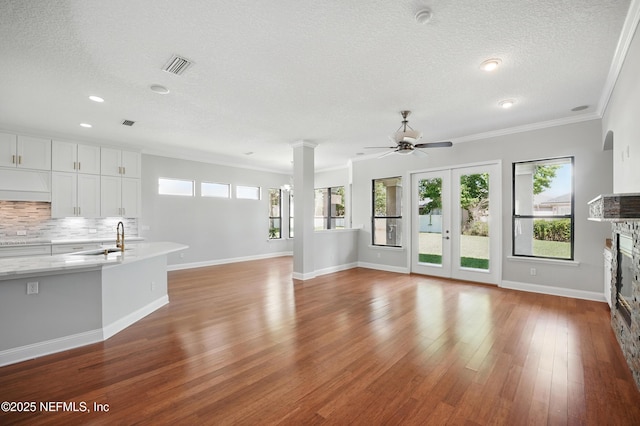 10065 Ecton Ln, Jacksonville, FL 32246 - unfurnished living room featuring a ceiling fan, a textured ceiling, a stone fireplace, baseboards, and a sink