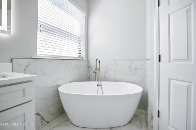 10065 Ecton Ln, Jacksonville, FL 32246 - bathroom with marble tiled floors, tile walls, vanity, a freestanding tub, and wainscoting