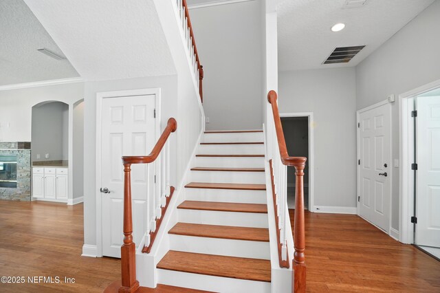 10065 Ecton Ln, Jacksonville, FL 32246 - staircase with wood finished floors, a textured ceiling, a fireplace, baseboards, and recessed lighting