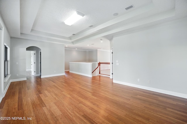 10065 Ecton Ln, Jacksonville, FL 32246 - unfurnished room featuring a tray ceiling, arched walkways, light wood finished floors, and baseboards