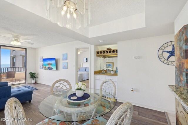 3360 Ocean Shore Blvd Unit 3070, Ormond Beach, FL 32176 - dining room featuring wood finished floors, a ceiling fan, baseboards, a textured ceiling, and a chandelier