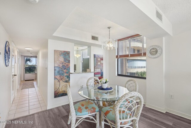 3360 Ocean Shore Blvd Unit 3070, Ormond Beach, FL 32176 - dining space with a chandelier, wood finished floors, baseboards, a textured ceiling, and a tray ceiling