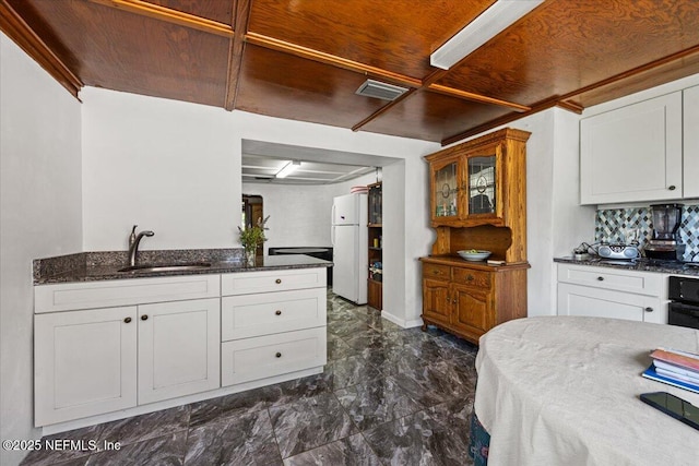 8615 2nd Ave, Jacksonville, FL 32208 - kitchen with a sink, dark marble finish floors, freestanding refrigerator, dark stone countertops, and white cabinetry