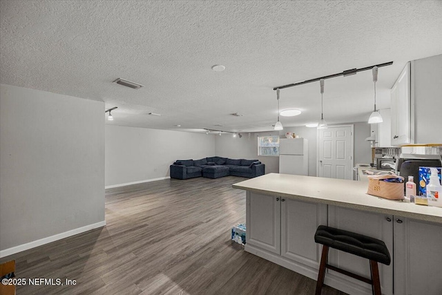 8615 2nd Ave, Jacksonville, FL 32208 - kitchen featuring freestanding refrigerator, dark wood-type flooring, a peninsula, a textured ceiling, and light countertops