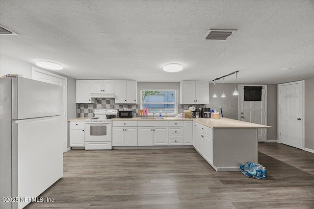 8615 2nd Ave, Jacksonville, FL 32208 - kitchen with white appliances, a peninsula, white cabinetry, a sink, and wood finished floors