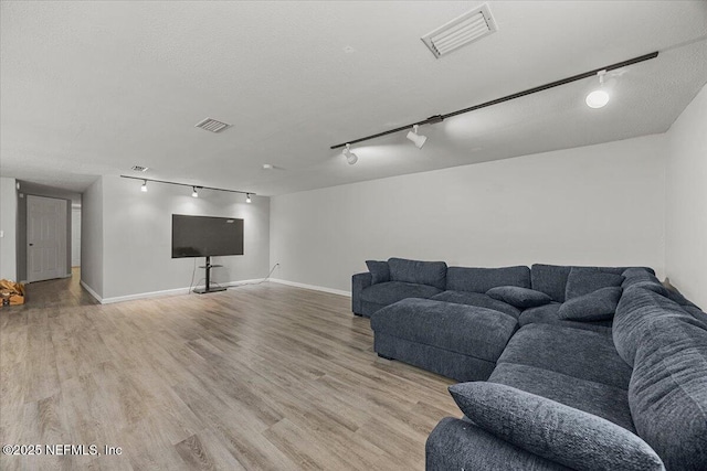 8615 2nd Ave, Jacksonville, FL 32208 - living room featuring rail lighting, light wood-style floors, and baseboards