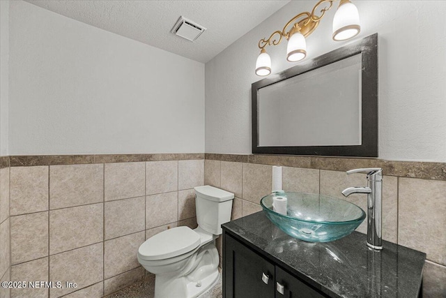 8615 2nd Ave, Jacksonville, FL 32208 - bathroom featuring tile walls, vanity, wainscoting, toilet, and a textured ceiling