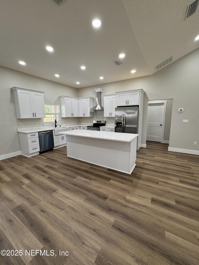 37280 New Oak St, Hilliard, FL 32046 - kitchen featuring appliances with stainless steel finishes, wall chimney exhaust hood, baseboards, a kitchen island, and white cabinets