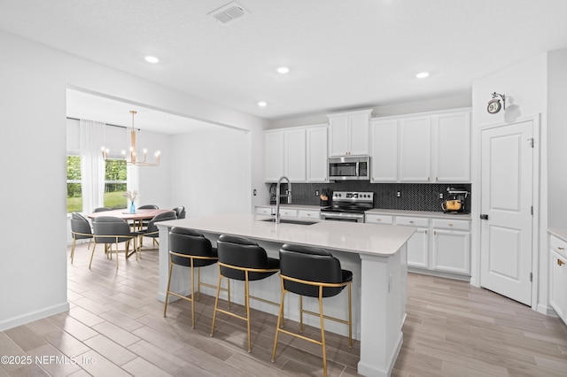 7242 Calamint Ave, Jacksonville, FL 32219 - kitchen featuring appliances with stainless steel finishes, a sink, a chandelier, tasteful backsplash, and a kitchen bar