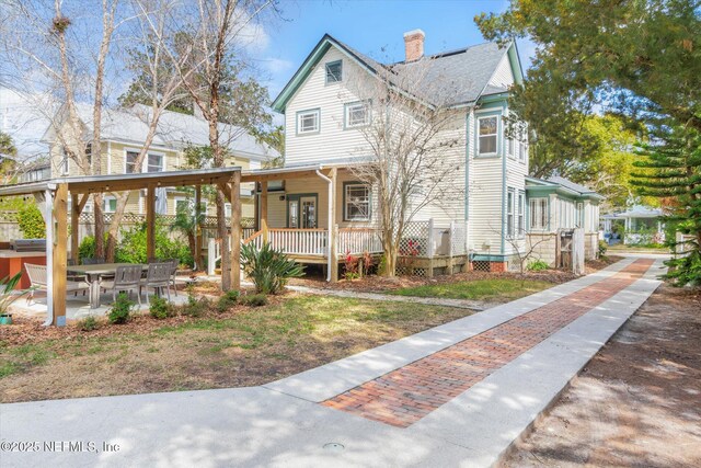 24 Sevilla St, Saint Augustine, FL 32084 - view of front facade featuring a chimney, covered porch, and a patio