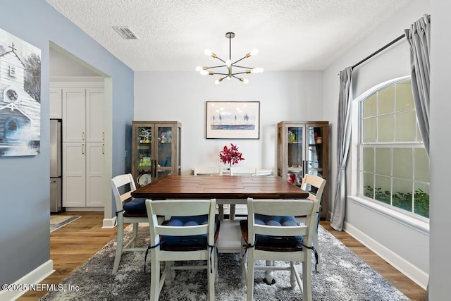 1252 Paradise Pond Rd, Saint Augustine, FL 32092 - dining area with a chandelier, light wood-style floors, a textured ceiling, and baseboards