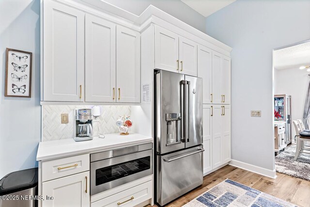1252 Paradise Pond Rd, Saint Augustine, FL 32092 - kitchen with appliances with stainless steel finishes, light wood-style flooring, backsplash, light countertops, and white cabinets
