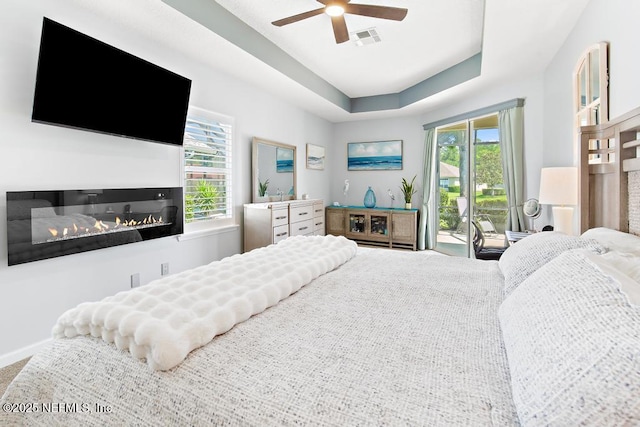 1252 Paradise Pond Rd, Saint Augustine, FL 32092 - bedroom featuring access to exterior, multiple windows, a glass covered fireplace, and ceiling fan