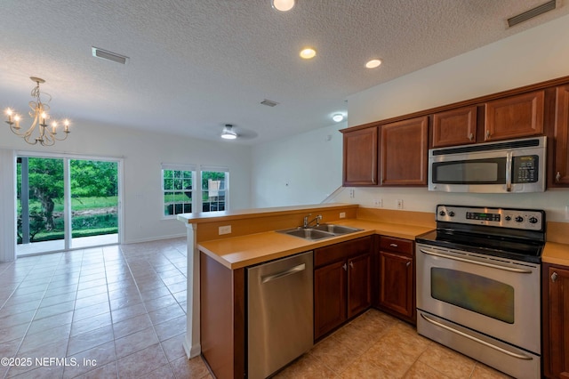 1843 Biscayne Bay Cir, Jacksonville, FL 32218 - kitchen featuring stainless steel appliances, a sink, a peninsula, a chandelier, and a textured ceiling