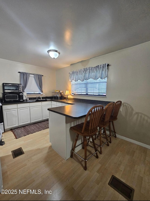 104 Palm Dr, Georgetown, FL 32139 - kitchen with a peninsula, dark countertops, light wood-style flooring, and white cabinetry