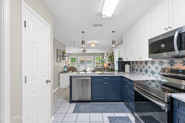 1500 Marsh Rabbit Way, Fleming Island, FL 32003 - kitchen with stainless steel appliances, a peninsula, blue cabinetry, open floor plan, and white cabinets