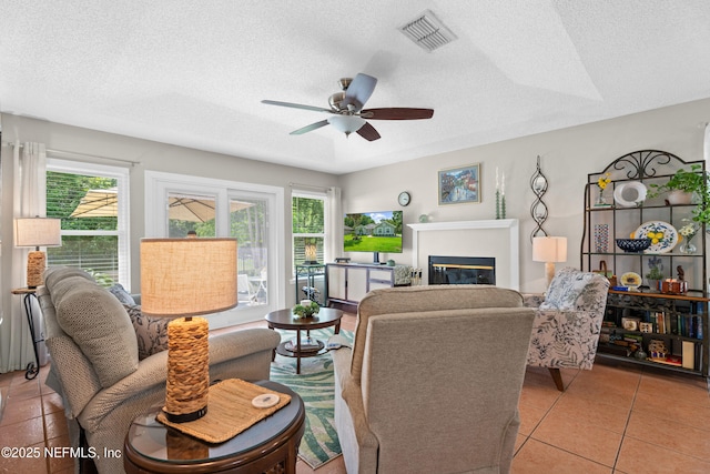 1500 Marsh Rabbit Way, Fleming Island, FL 32003 - living area featuring plenty of natural light, ceiling fan, a textured ceiling, a glass covered fireplace, and light tile patterned flooring