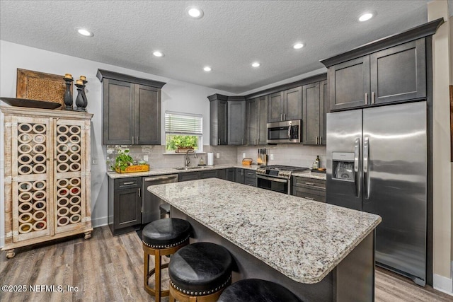5801 SE County Road 21b, Keystone Heights, FL 32656 - kitchen with stainless steel appliances, wood finished floors, light stone countertops, a center island, and a textured ceiling