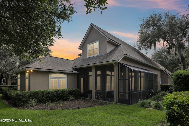 4640 Tuscan Wood Ct, Saint Augustine, FL 32092 - rear view of property featuring a sunroom, roof with shingles, stucco siding, and a lawn