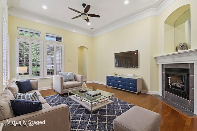 4640 Tuscan Wood Ct, Saint Augustine, FL 32092 - living room featuring a ceiling fan, crown molding, a tiled fireplace, dark wood-type flooring, and a towering ceiling