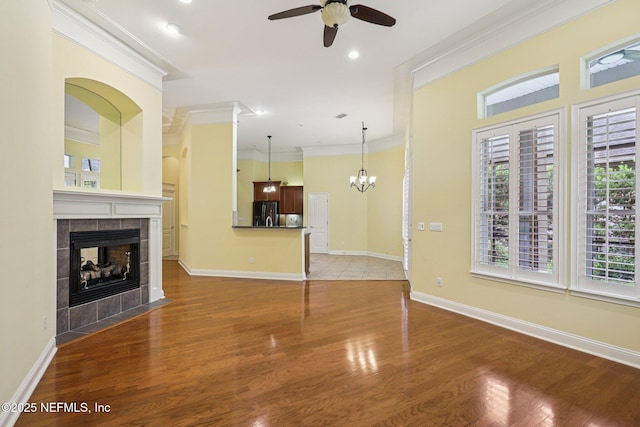 4640 Tuscan Wood Ct, Saint Augustine, FL 32092 - unfurnished living room with a ceiling fan, crown molding, a tile fireplace, wood finished floors, and a chandelier