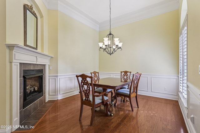 4640 Tuscan Wood Ct, Saint Augustine, FL 32092 - dining area with crown molding, dark wood-style floors, a tile fireplace, wainscoting, and a chandelier