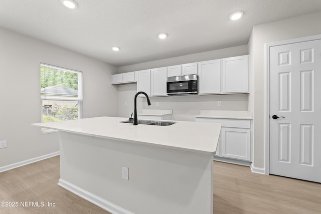 5969 Flicker Ave, Jacksonville, FL 32219 - kitchen featuring a sink, stainless steel microwave, white cabinets, light wood-style flooring, and recessed lighting