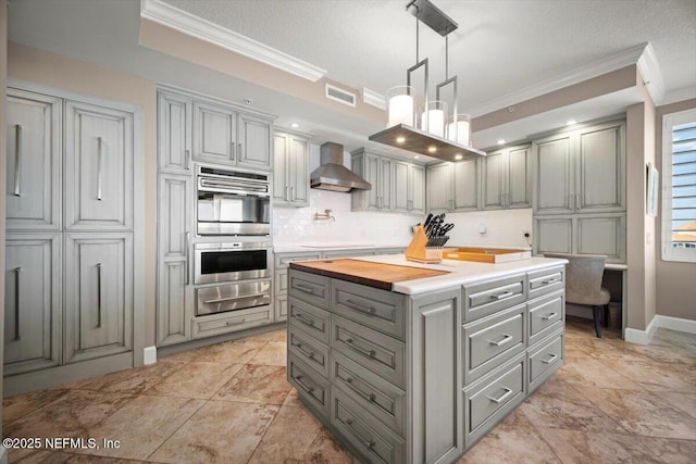 1031 1st St S Unit 1202, Jacksonville Beach, FL 32250 - kitchen featuring wall chimney exhaust hood, a warming drawer, gray cabinetry, double oven, and crown molding