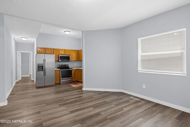 209 E 17th St, Jacksonville, FL 32206 - kitchen featuring stainless steel appliances, wood finished floors, light countertops, and brown cabinetry