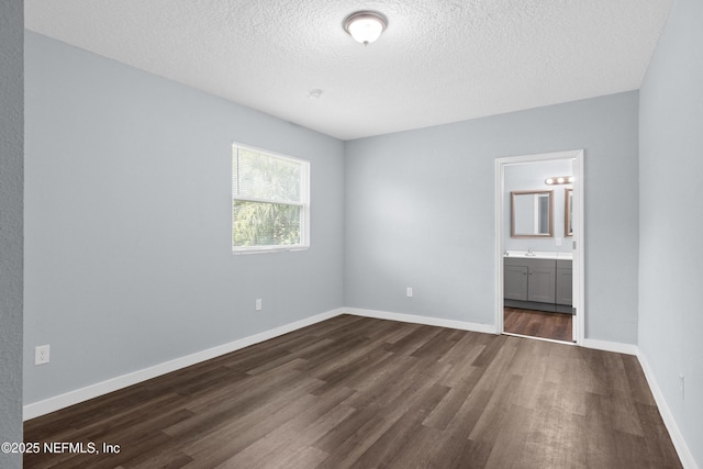 209 E 17th St, Jacksonville, FL 32206 - unfurnished bedroom with dark wood finished floors, a textured ceiling, a sink, baseboards, and ensuite bathroom