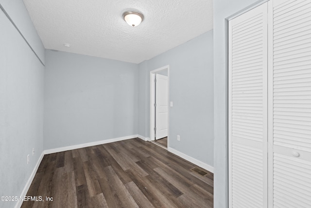 209 E 17th St, Jacksonville, FL 32206 - unfurnished bedroom with dark wood-type flooring, a textured ceiling, baseboards, and a closet